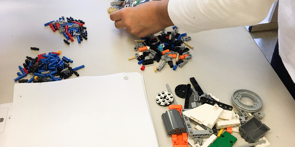 Photo of student's hand sifting through spare robotics parts lying on the table