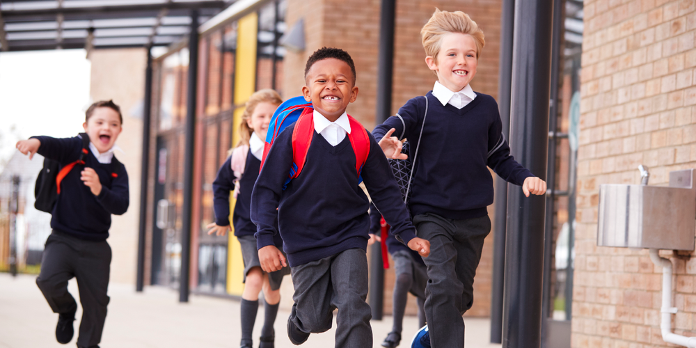 Photo of young students in uniform running back to school