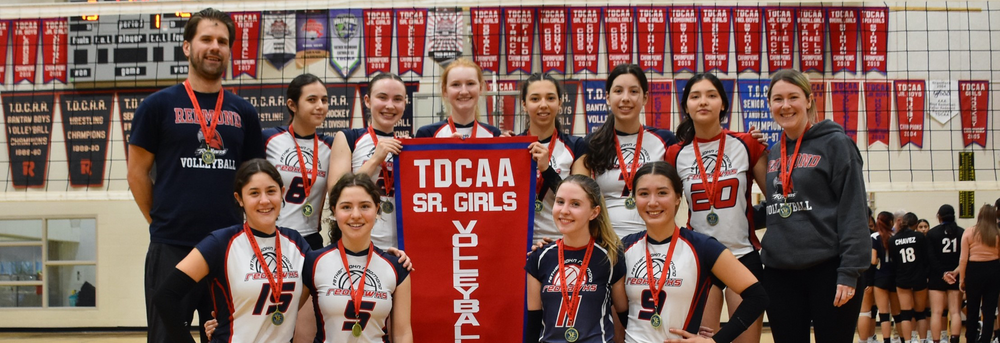 Photo of Father John Redmond's Senior Girls Volleyball Team posing with their TDCAA championship banner, along with the team coaches