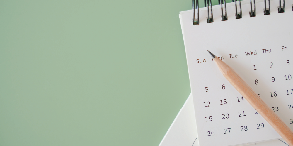 An image consists of a green background, pencil and calendar.
