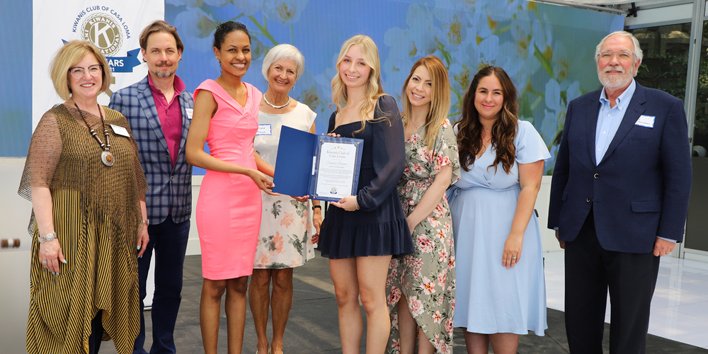 Photo of Claudia receiving the award from the Kiwanis International members.