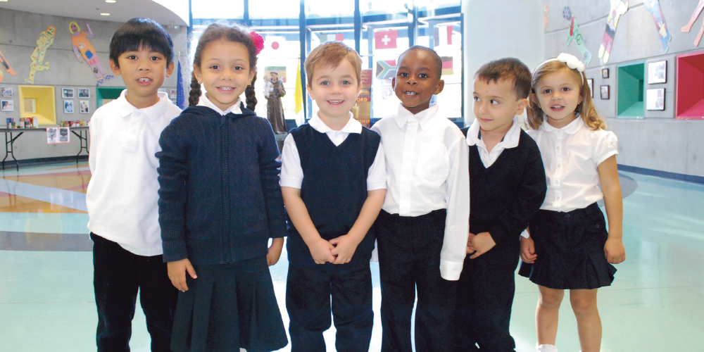 A group of 6 students in navy and white uniform smiling at the camera.