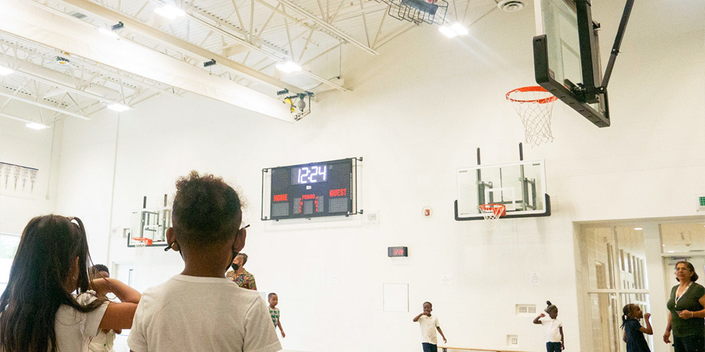 Photo of elementary students in uniform in the school gym, with teachers supervising them