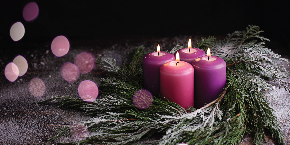 An image consists of 3 purple candles and 1 pink candle inside a wreath. 