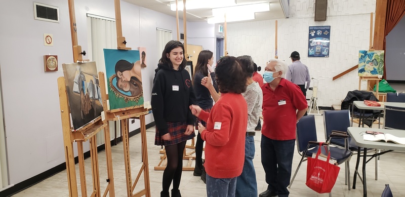 Students showcase art exhibits at Piece Out presentation while members of the school community look at the art