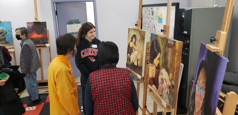Students showcase art exhibits at Piece Out presentation while members of the school community look at the art