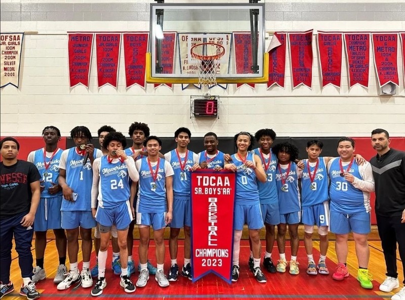 St. Joan of Arc's Senior Boys AA Basketball team posing with their TDCAA championship banner, along with their coaches