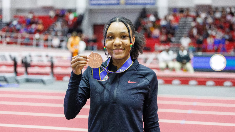 Photo of Mikeisha holding up a bronze medal  that she's wearing