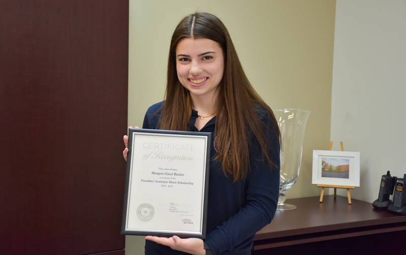 Photo of Morgen holding her framed certificate of recognition.