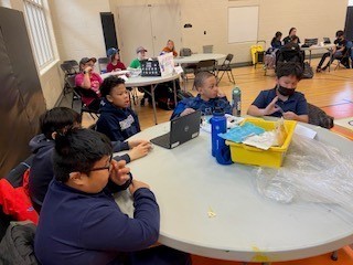 St. Marguerite Bourgeoys students sitting around a table brainstorming their robotics project.