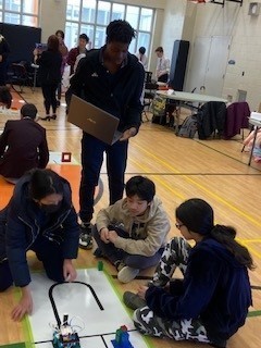 St. Marguerite Bourgeoys students sitting on the floor plotting their robot's path through the assigned course.