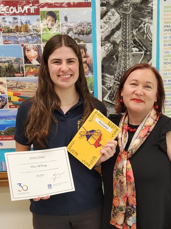 Photo of winning student holding up award certificate and book