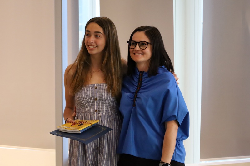 Photo of winning student with awarded certificate and book