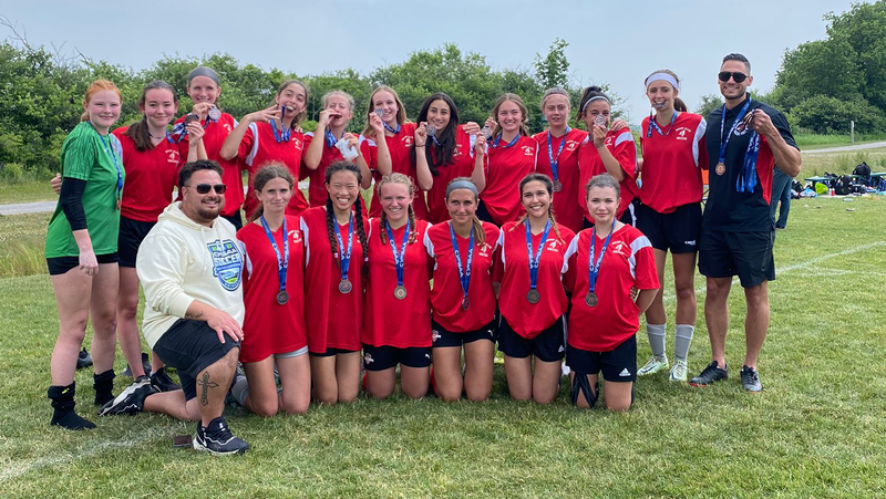 Group photo of the Bishop Allen varsity girls soccer team with their coaches Michael and Nabil