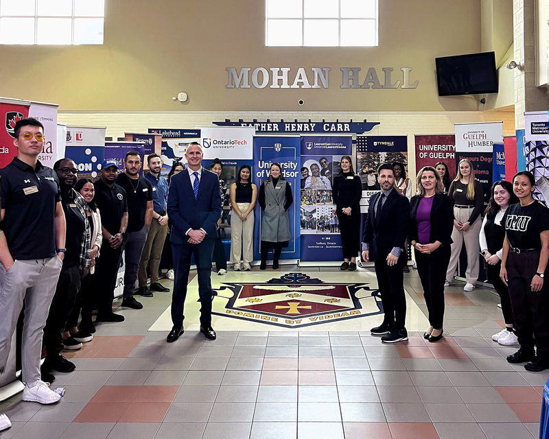Father Henry Carr students and staff pose with fair presenters in Mohan Hall where the fair was held