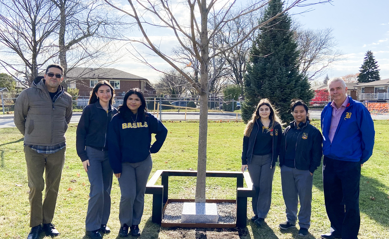 St. Basil-The-Great Staff and Students stand with the Sugar Maple Tree planted in remembrance of Canadians serving in the armed forces, with the new memorial stone at the base of it