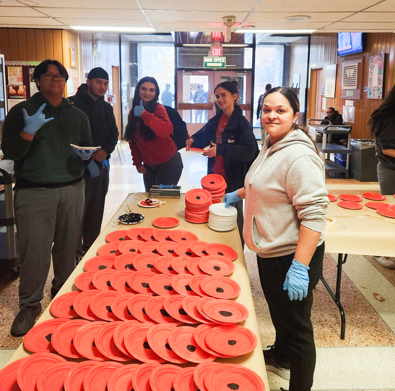 Newman staff hand out plates and students paint plates to resemble poppies