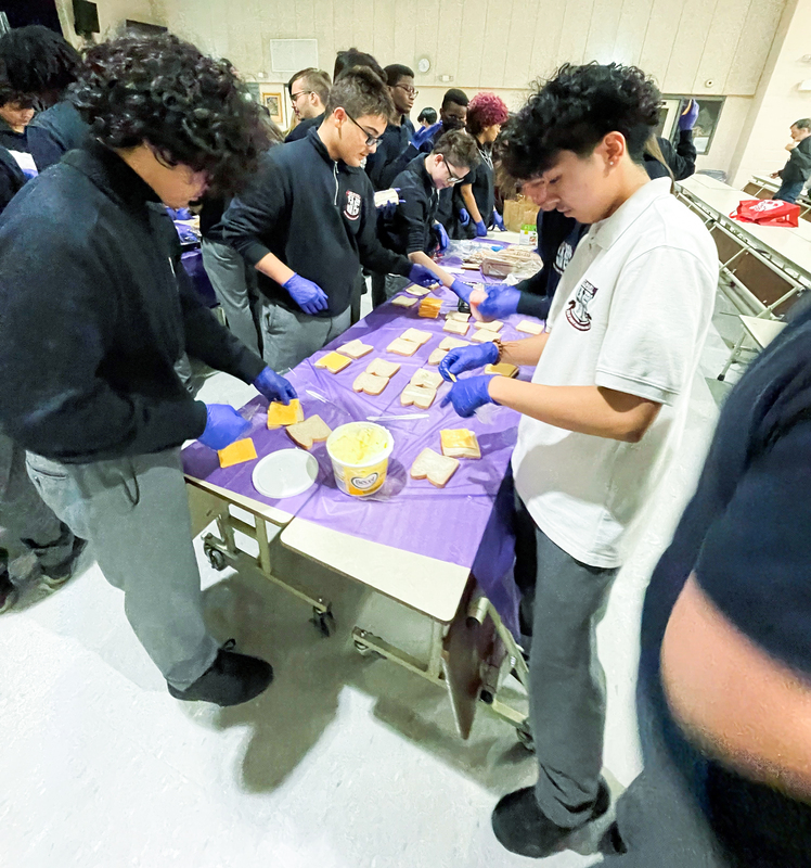 St. Mary Catholic Academy students gathered around a table wearing gloves and preparing sandwiches at Good Shepherd Ministries